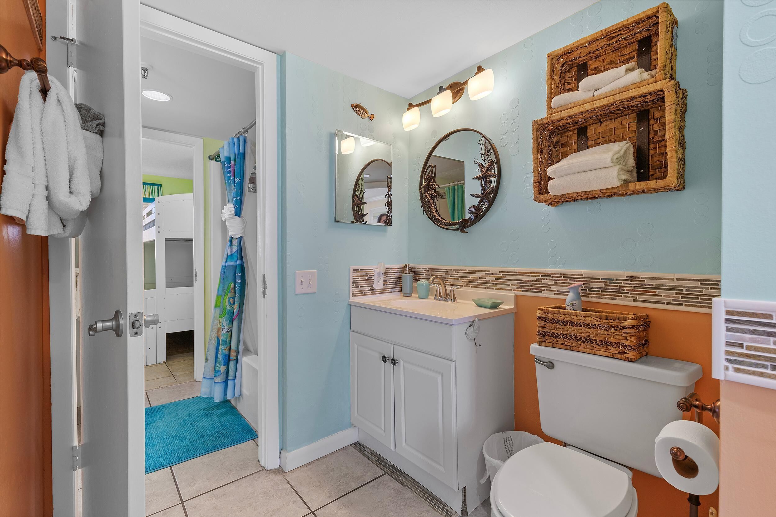 A bathroom with a white sink, two mirrors, a toilet, and a shower curtain.