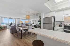 A modern kitchen with a large island, stainless steel appliances, and a view of the ocean. - Oceania Plaza 502 (New Smyrna Beach)