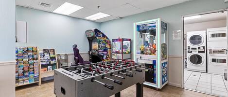A room with a foosball table, a washing machine, and a vending machine.