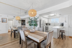 A modern kitchen with white cabinets, a stainless steel refrigerator, and a built-in oven. - Oceania Plaza 502 (New Smyrna Beach)
