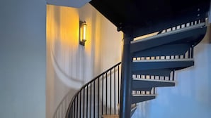 A modern spiral staircase with wooden steps and black railings, leading to a landing with a wall-mounted light fixture. - Beautiful vacation house in the middle of Crested Butte (Crested Butte)
