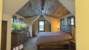 A bedroom with a sloped ceiling, a bed, a dresser, a chair, and a potted plant. - Beautiful vacation house in the middle of Crested Butte (Crested Butte)