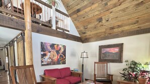 A spacious living room with wooden furniture, a red sofa, and a high ceiling with exposed beams. - Beautiful vacation house in the middle of Crested Butte (Crested Butte)