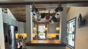 A kitchen with wooden floors, a central island with stools, hanging pots, and a view of the dining area. - Beautiful vacation house in the middle of Crested Butte (Crested Butte)
