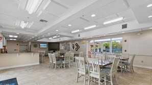 Un vaste espace dédié à la restauration, avec de nombreuses tables et chaises, un comptoir d’accueil et une vue sur l’extérieur grâce à de grandes fenêtres.