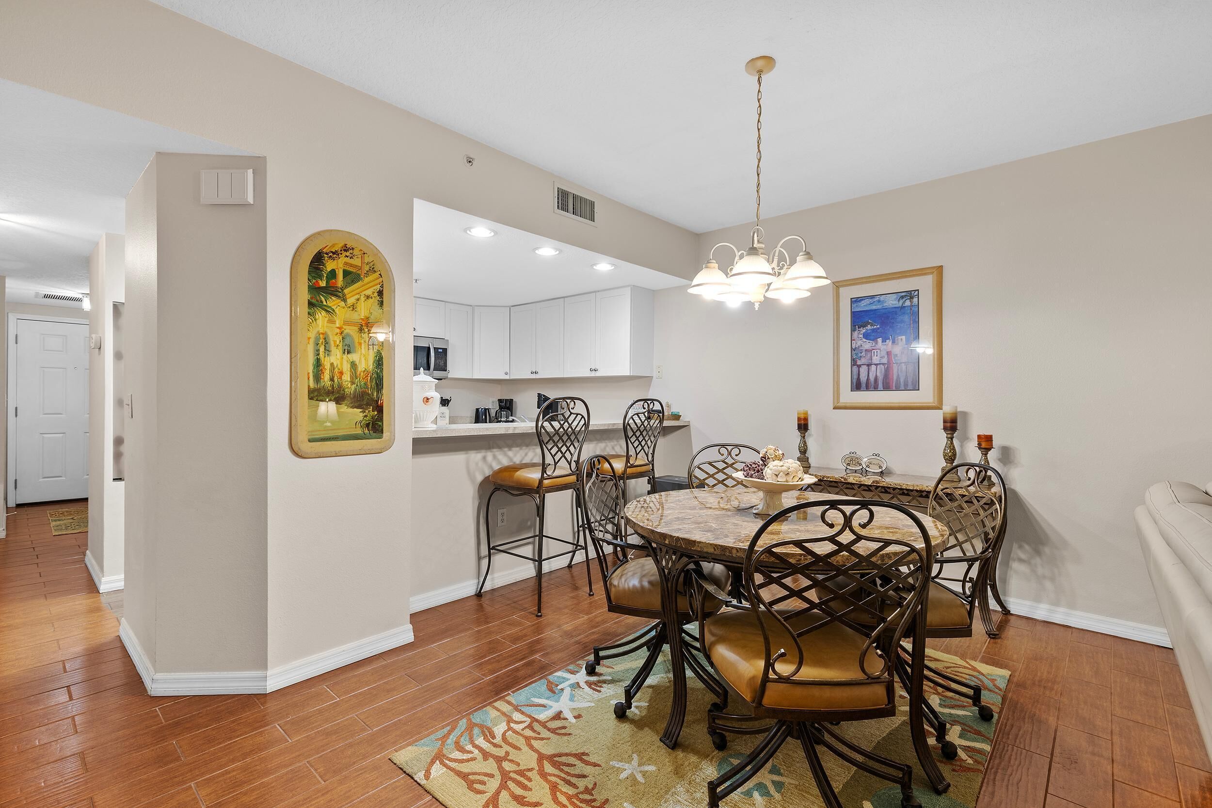 A dining area with a round table, chairs, and a chandelier.