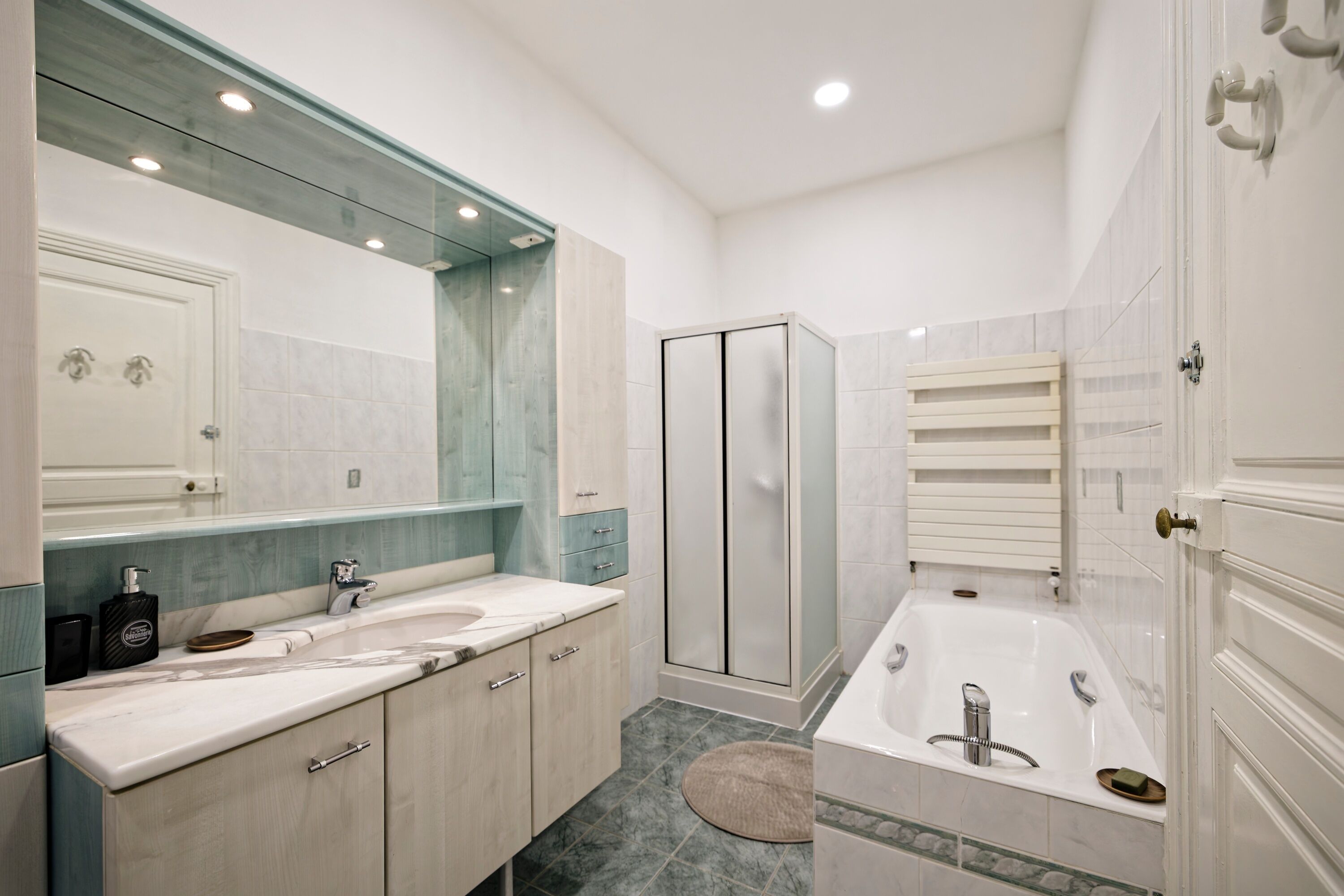 Un baño moderno con lavamanos doble, un espejo grande, ducha a ras de suelo y bañera.