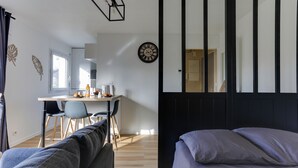 Una camera moderna con un letto, un divano, una scrivania e sedie, e una sveglia a muro.