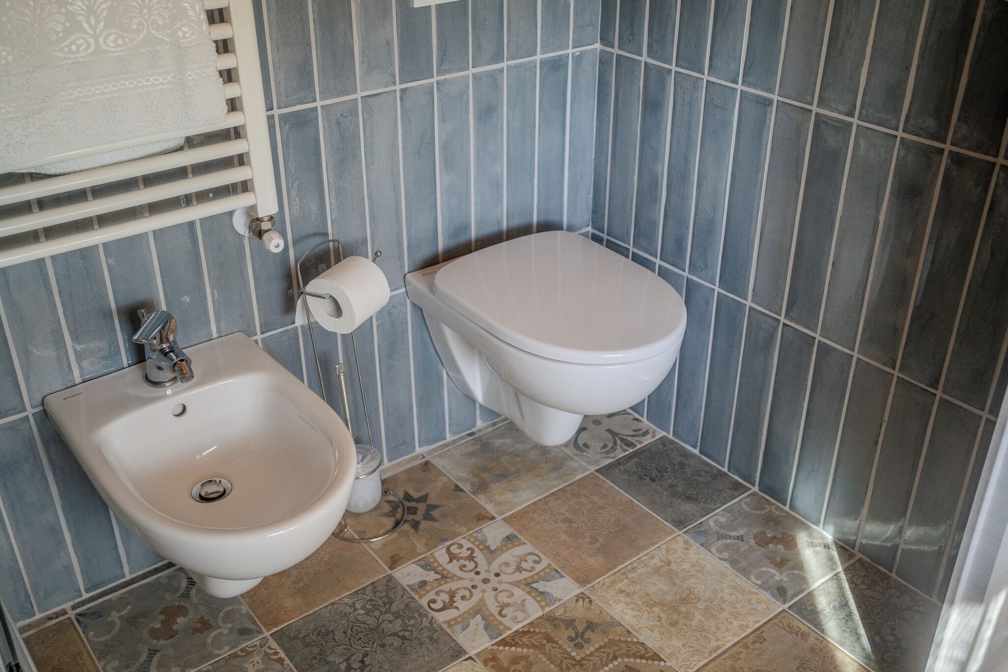 Ein Badezimmer mit einer Bidet-Funktion, Toilette und einem Fliesenboden mit Muster.