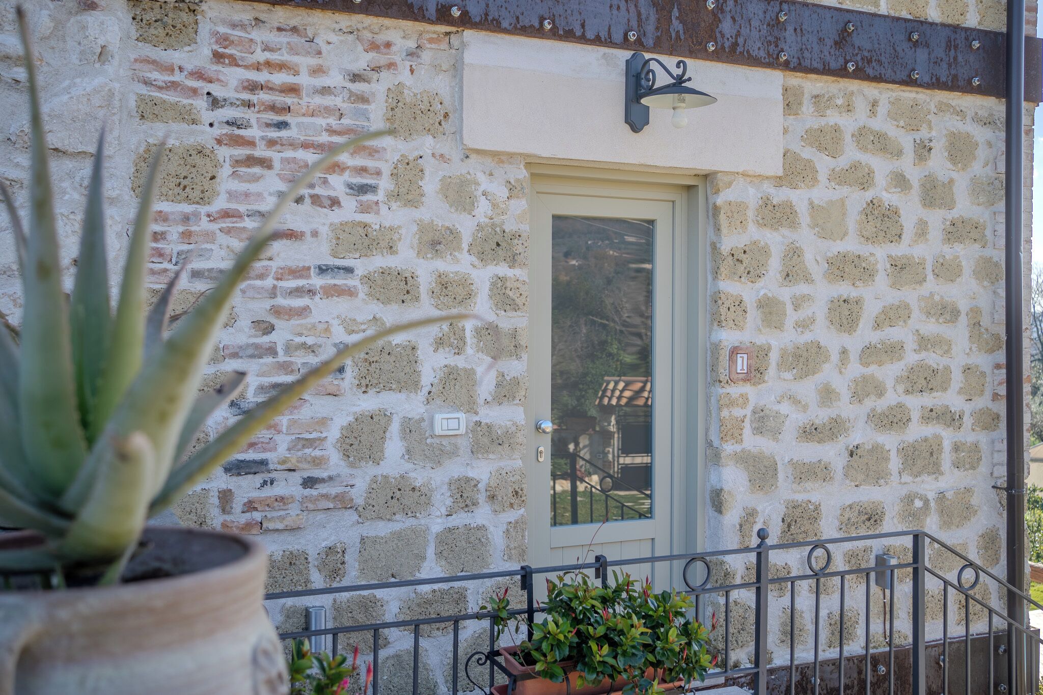 A stone building with a door and a small balcony with potted plants.