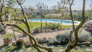 Una piscina rodeada por un jardín ajardinado con diversas plantas y rocas.