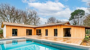 Ein modernes Holzhaus mit Pool, großen Fenstern und einer Terrassenfläche.