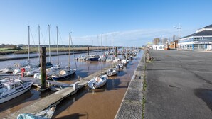A marina with multiple boats docked along a concrete quay, a clear sky, and a building with a sign in the background. - Rosamel - Studio à 1km de la gare, proche port (Etaples-sur-Mer)