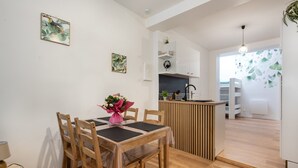 A modern kitchen with wooden cabinetry, a central island, and a dining area with a table and chairs. - Rosamel - Studio à 1km de la gare, proche port (Etaples-sur-Mer)