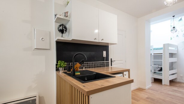 A compact kitchen with white cabinets, a black backsplash, and a wooden countertop. - Rosamel - Studio à 1km de la gare, proche port (Etaples-sur-Mer)