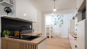A modern kitchen with a central island, wooden cabinets, and a black backsplash. - Rosamel - Studio à 1km de la gare, proche port (Etaples-sur-Mer)