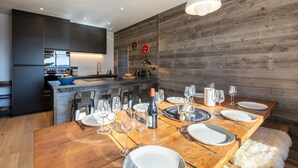 Una cocina moderna con armarios oscuros, una isla de madera y un comedor listo para una comida.
