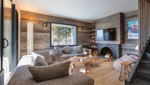 Una sala moderna con chimenea, paredes de madera y un ventanal grande.