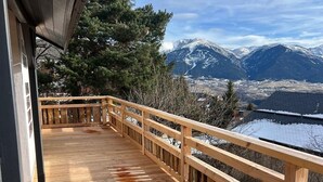 Una terraza de madera con vistas a montañas nevadas.