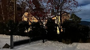 Un paisaje cubierto de nieve con un edificio iluminado al fondo.
