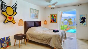 A bedroom with a bed, a nightstand, a ceiling fan, and a view of a swimming pool.
