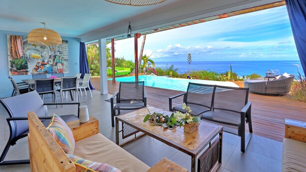 A spacious outdoor area with a pool, wooden deck, and seating arrangements.