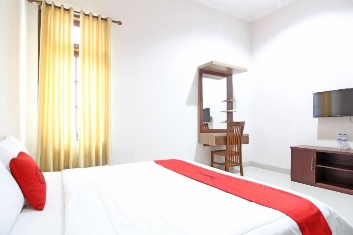 A hotel room with a bed, a desk, a chair, a TV, and a wardrobe.