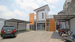 Un bâtiment moderne doté d’un abri pour voitures et d’une rangée de motos garées.