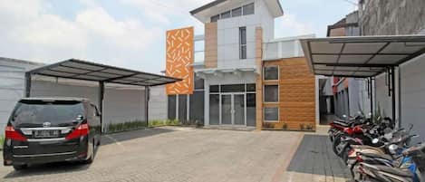 A modern building with a carport and a row of parked motorcycles.