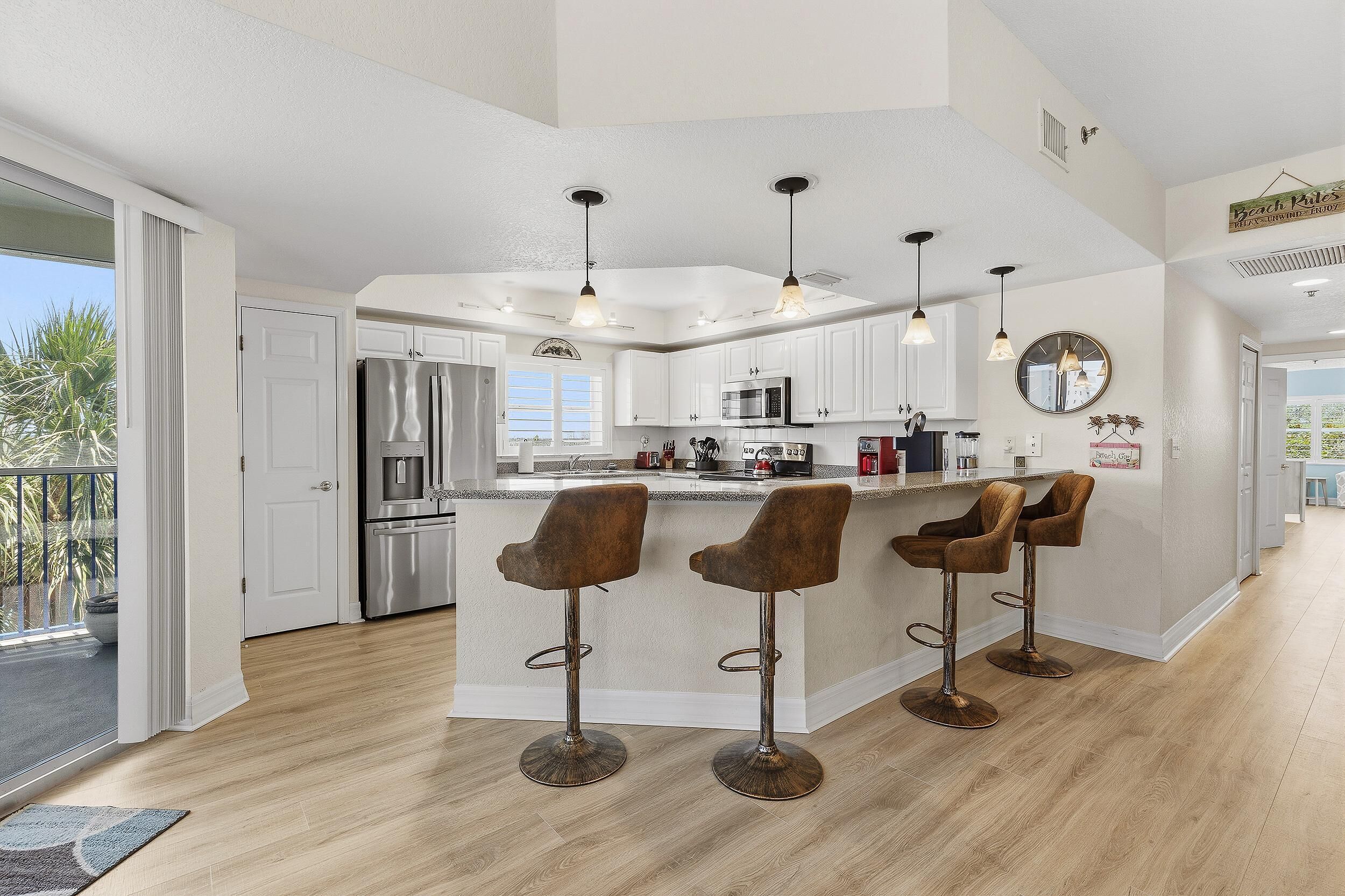 A modern kitchen with white cabinets, stainless steel appliances, and a central island with bar stools.