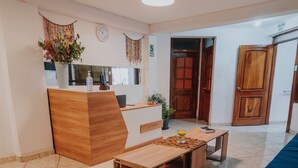 A modern reception area with a wooden desk, a blue sofa, and a tiled floor. - HOTEL LITAN (Cusco)
