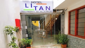 The entrance of Hotel Litan with a glass door, potted plants, and a red mat. - HOTEL LITAN (Cusco)