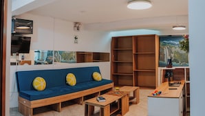 A modern living room with a blue sofa, wooden coffee table, and a kitchen area with a wooden counter and shelves. - HOTEL LITAN (Cusco)