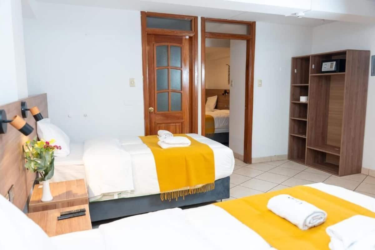 A hotel room with a bed, a wardrobe, a desk, and a nightstand.
