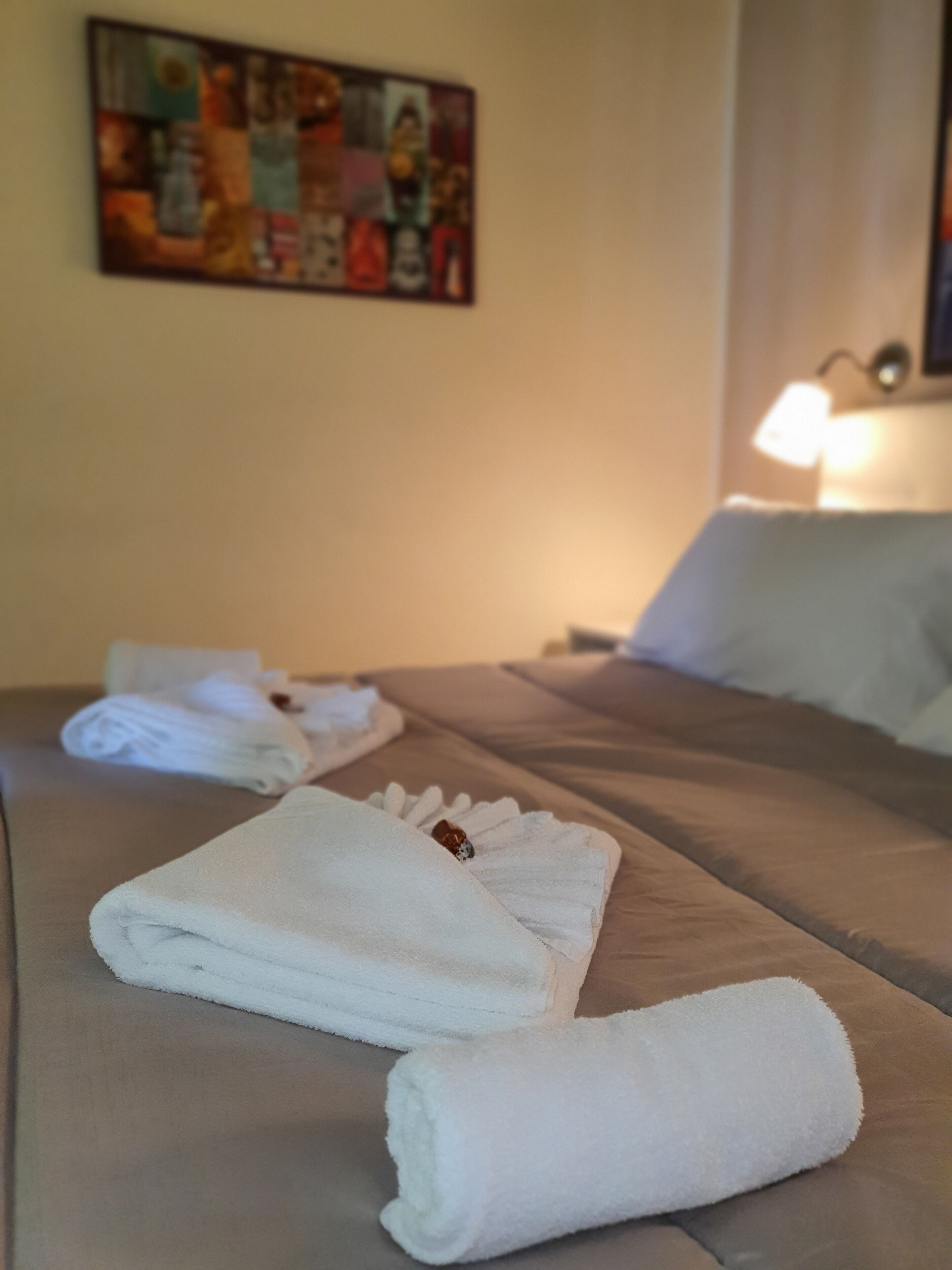 A neatly made bed with white towels and a painting on the wall.