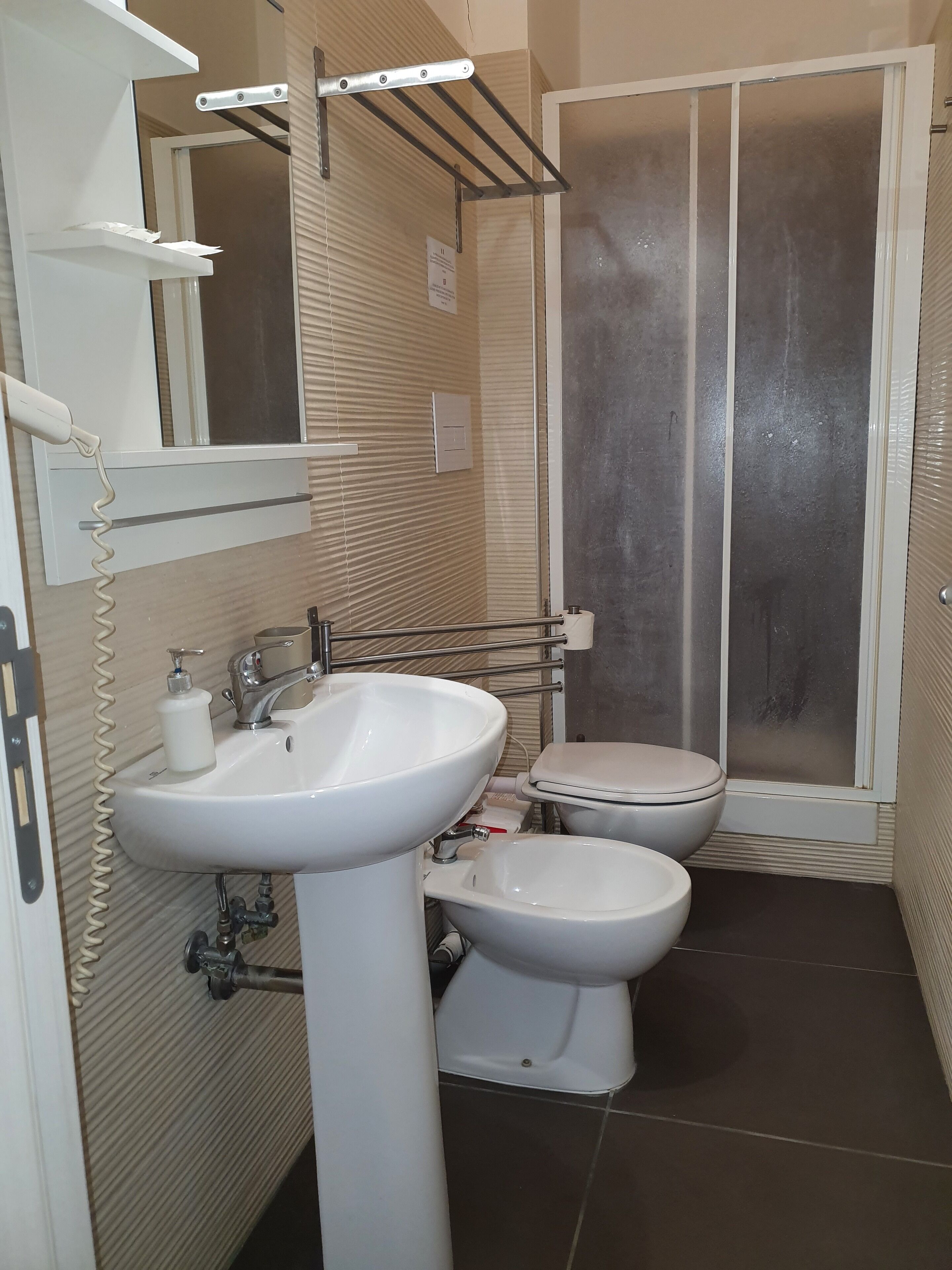 Une salle de bain avec un lavabo blanc, des toilettes et un espace douche.