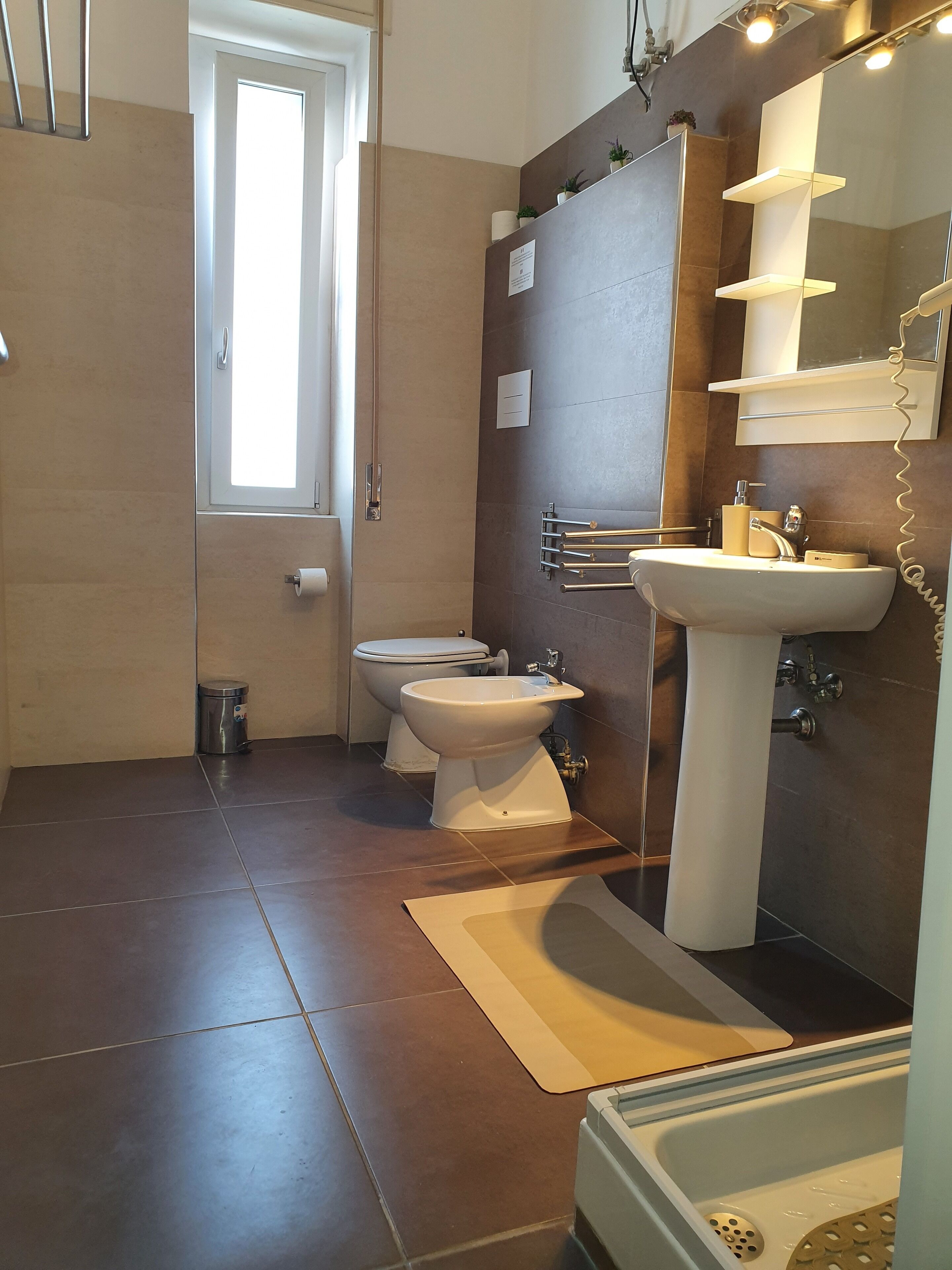 A modern bathroom with a toilet, bidet, sink, and bathtub.