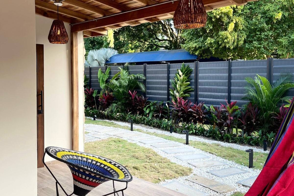 Una silla hamaca en un espacio exterior cubierto, con techo de madera y luces colgantes.