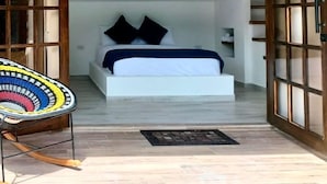 Un dormitorio con una cama, una lámpara colgante y vistas a través de una puerta de madera.