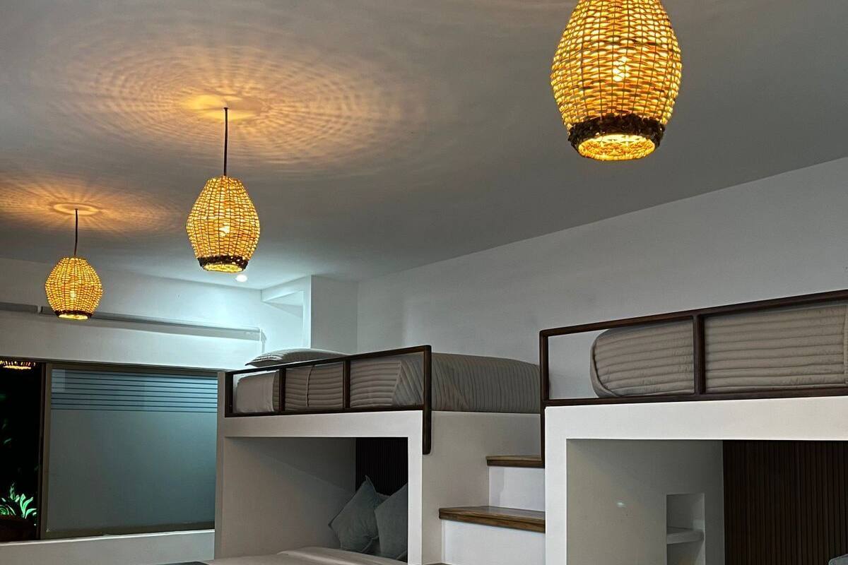 Un dormitorio moderno con literas, una escalera y lámparas colgantes.