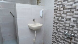 A bathroom with a white sink, a hand dryer, and a tiled shower area. - B type Cottage (Koroli)