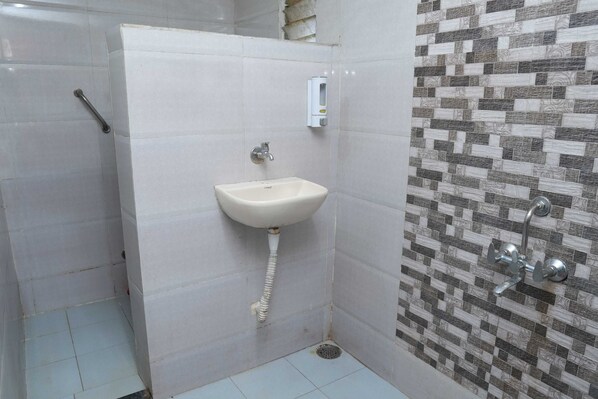 A bathroom with a white sink, a hand dryer, and a tiled shower area.