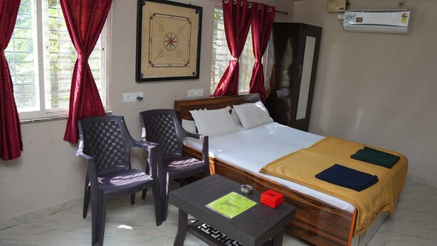 A hotel room with a bed, two chairs, a small table, and a framed picture on the wall. - B type Cottage (Koroli)