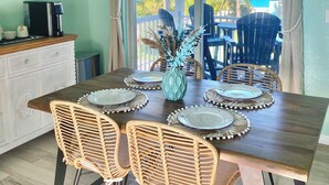 Een eetgedeelte met een houten tafel voor zes personen, omringd door rieten stoelen, een decoratieve vaas en een hanglamp.