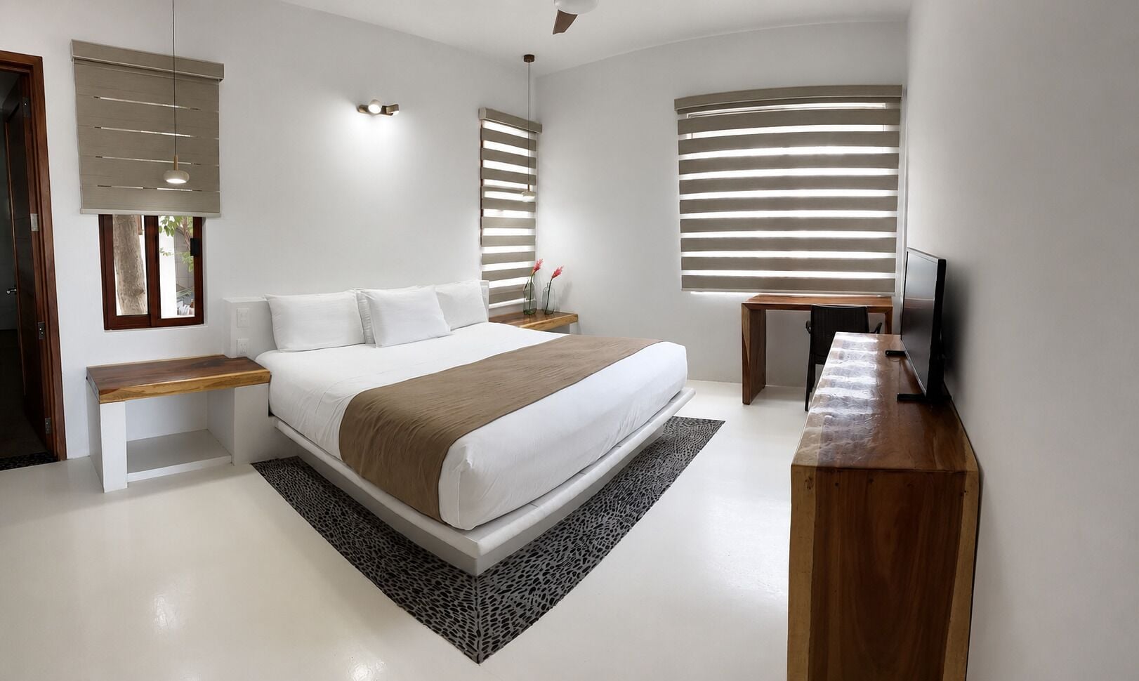 A modern bedroom with a large bed, bedside tables, a desk, and a television.