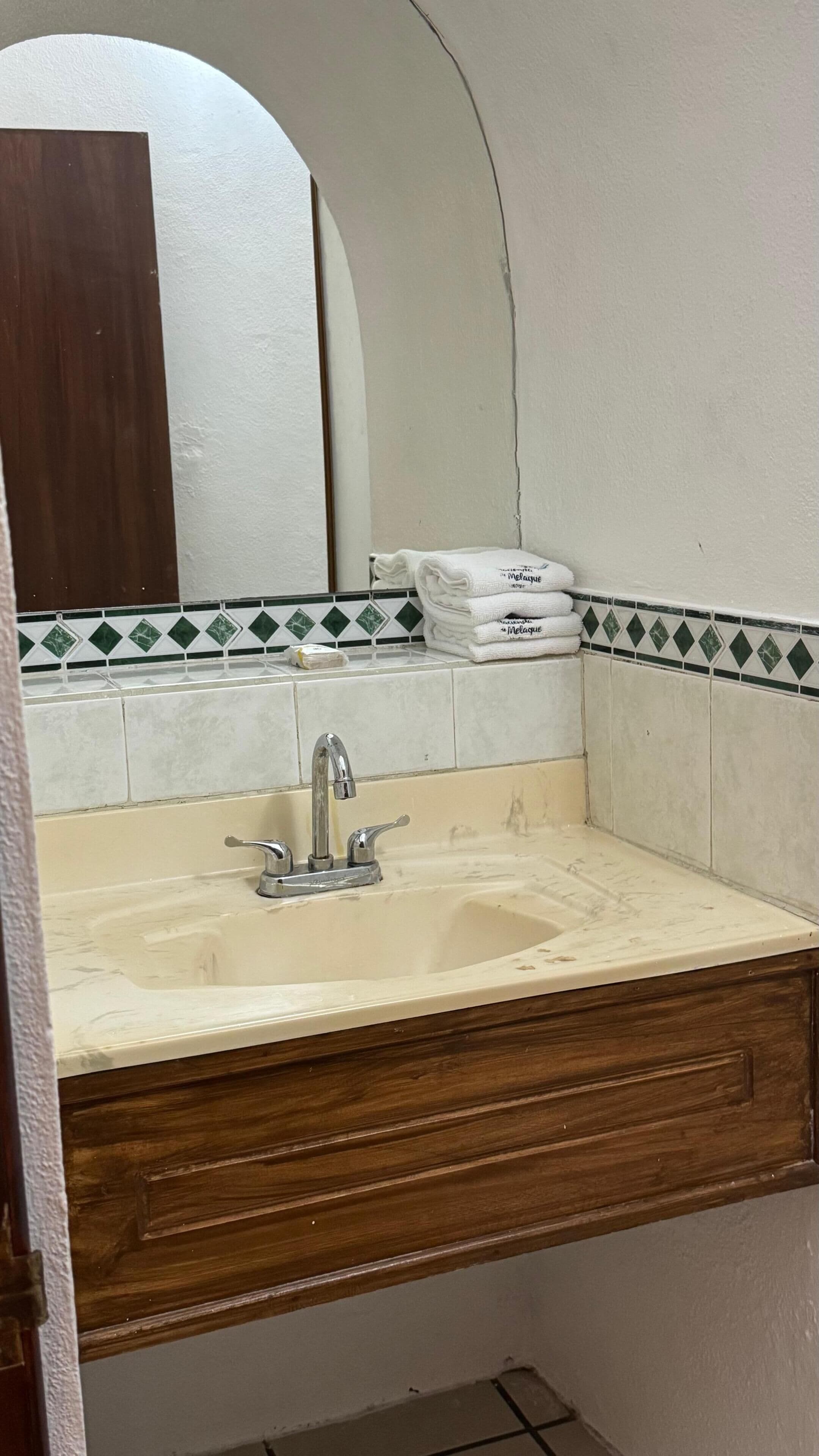A bathroom with a sink, mirror, and towel rack.