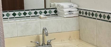 A bathroom with a sink, mirror, and towel rack.