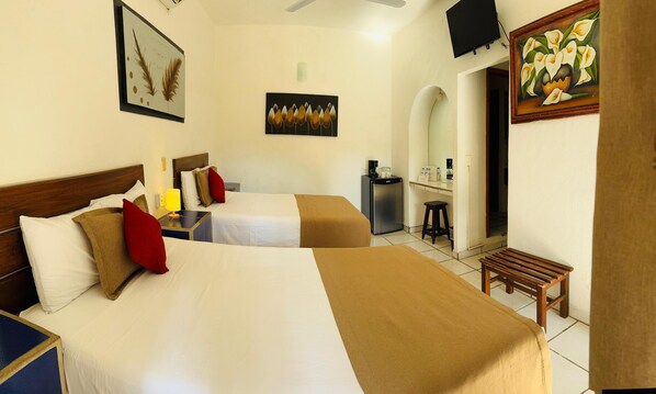 Ein Hotelzimmer mit zwei Betten, einem Schreibtisch, einem Sessel, einem Fernseher und Bildern an den Wänden.