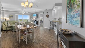 A spacious living area with a dining table, chairs, and a ceiling fan.