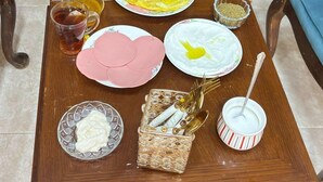 A dining table set with various dishes, including flatbreads, a salad, and a plate with a yellow egg. - PETRA BALCONY APARTMENT (Wadi Musa)